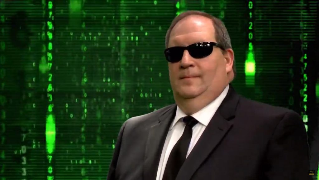 A person wearing a suit and sunglasses posing for the camera

Description automatically generated